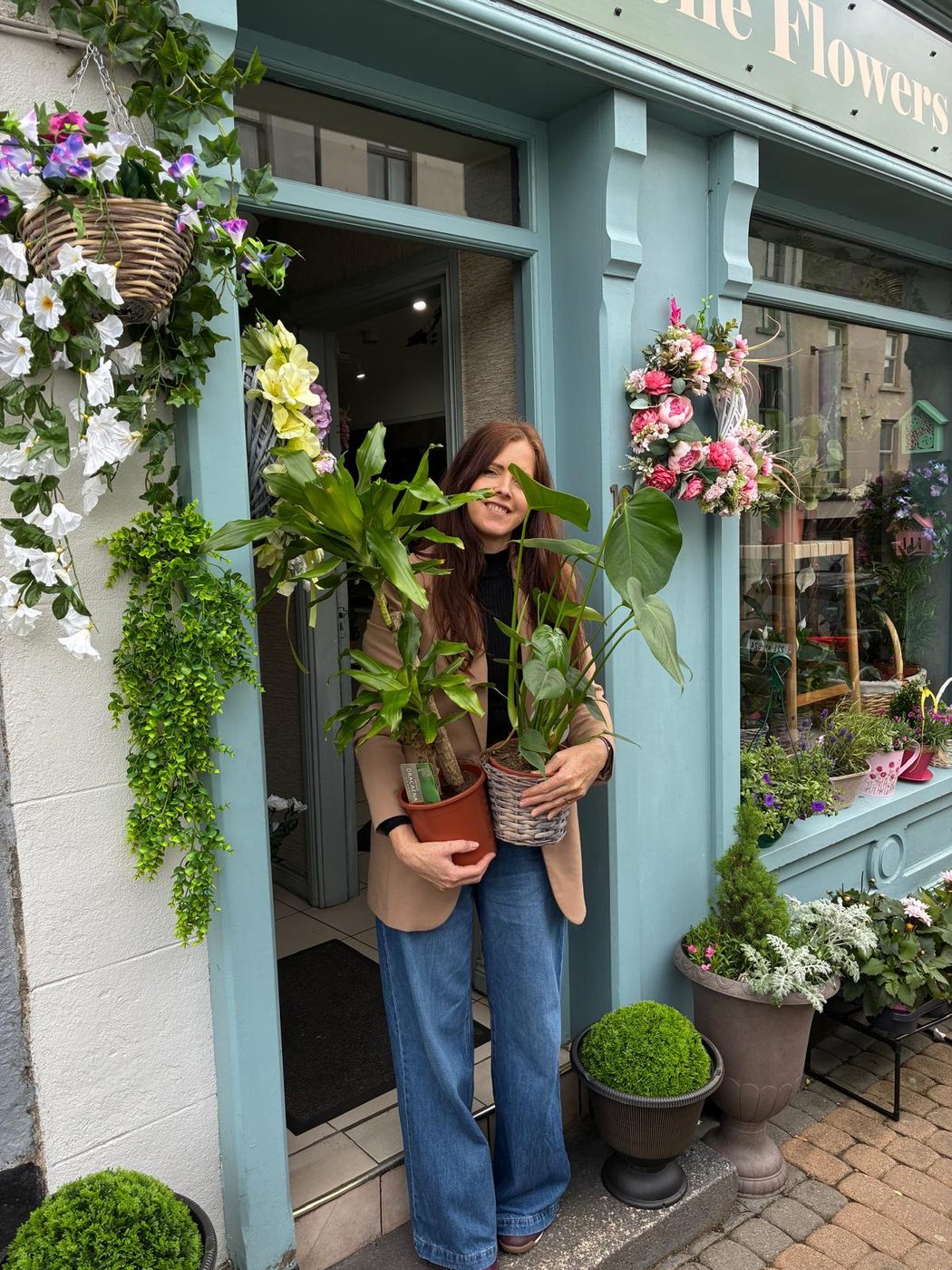 Jolie outside the shop in Monaghan, hanging baskets and wreaths either side of the door